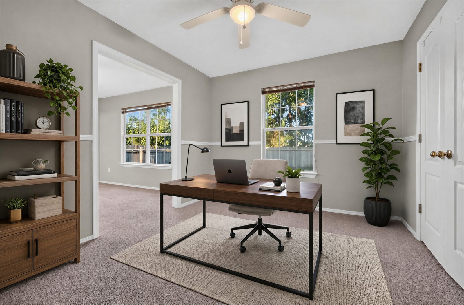 Office off the primary bedroom, virtually staged: two windows, a ceiling fan, and a doorway to the primary bedroom, shown with a digitally added desk, chair, and shelves