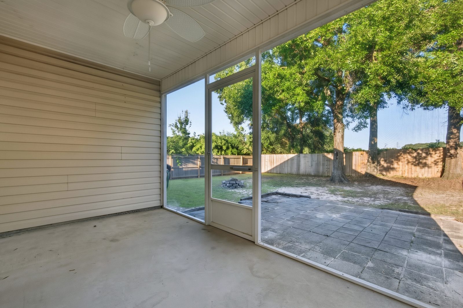 Inside the screened porch, looking out over the paver patio to the backyard